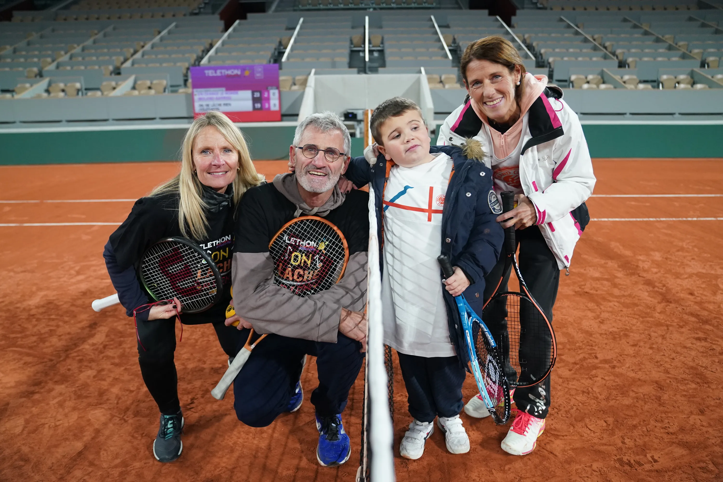 une famille prend la pose sur un cour de tennis en terre battue